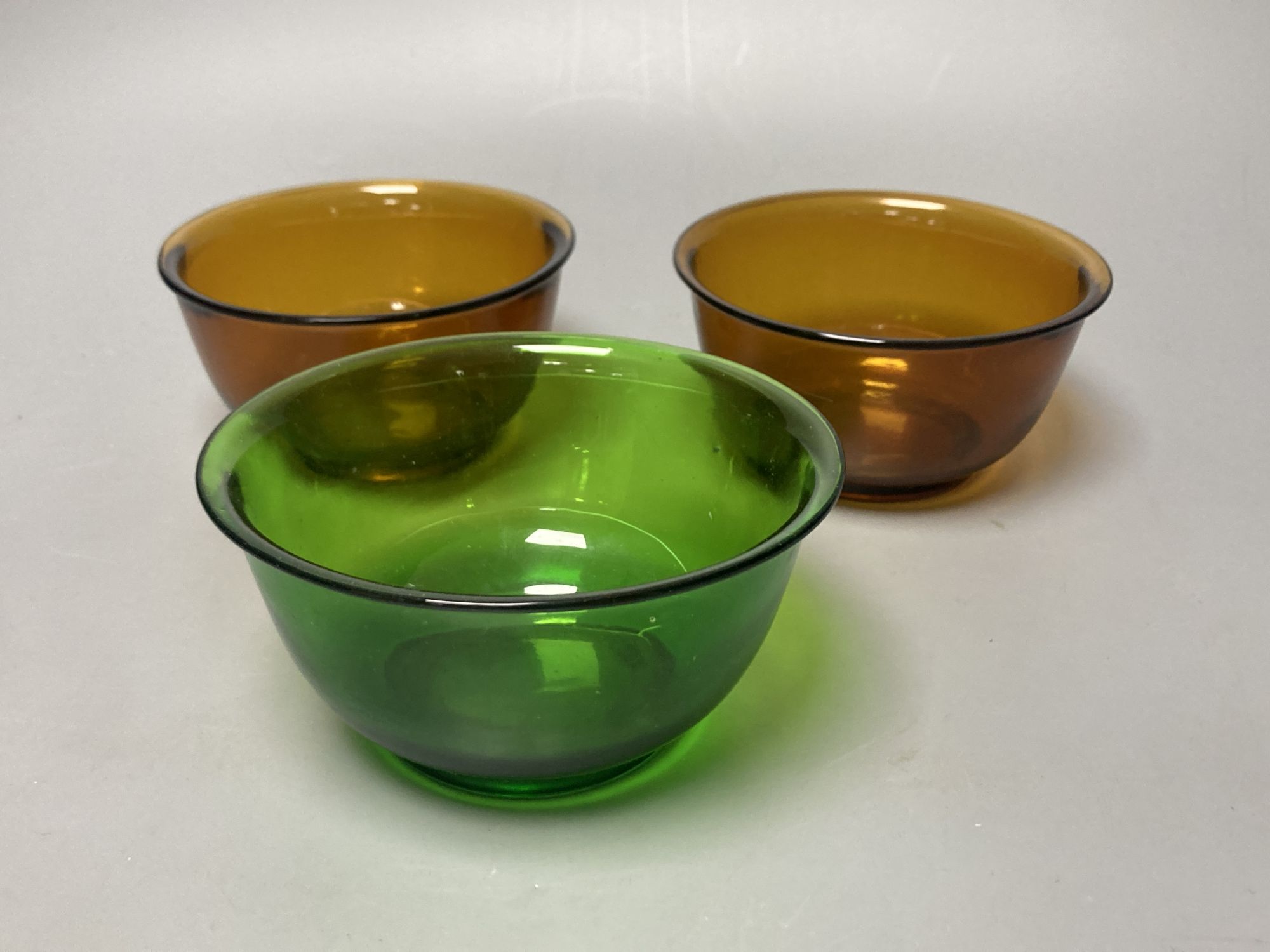 A pair of Chinese Beijing amber glass bowls, together with a similar green glass bowl, diameter 11cm